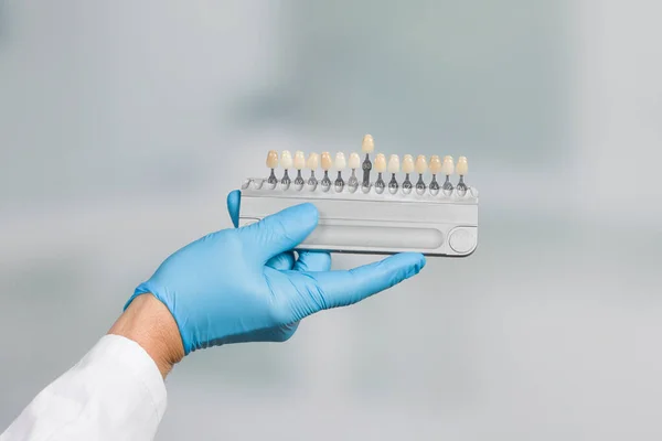 Diş beyazlatma ya da yapay diş implantı (implant) için diş kaplamasını kontrol etmek / belirlemek için gölgelik rehberli dişçi eli
