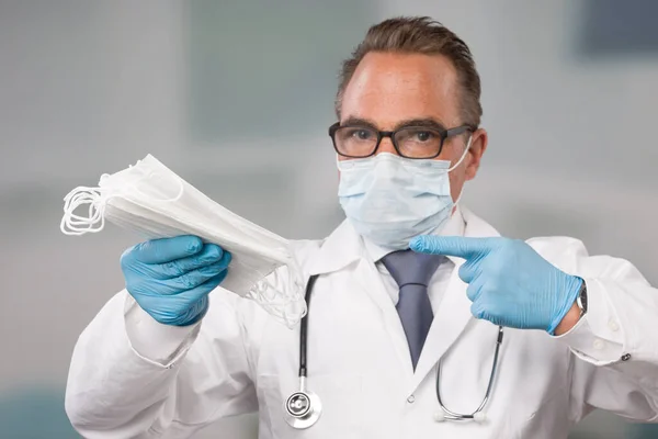 Mužský Lékař Maskou Lékařskými Rukavicemi Ukazuje Spoustu Masek Pro Ochranu — Stock fotografie