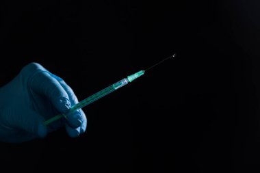 Doktorun elini siyah arka planda aşı şırıngası ile tıbbi eldivenlerle kapat.