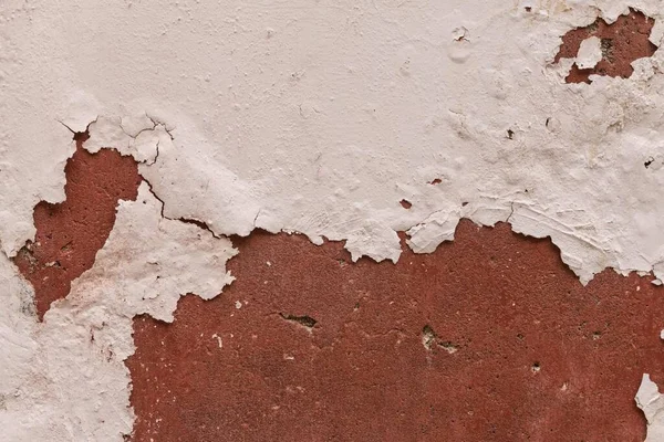 Kırık alçılı bir duvar, yerin altında kırmızı bir şey gösteriyor. 