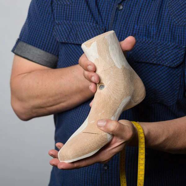 close-up of hands of orthopedic shoemaker presenting proudly an individual wooden last