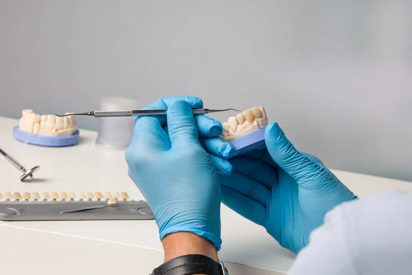 close-up of dental technician working with a brush on tooth crown in dental laboratory