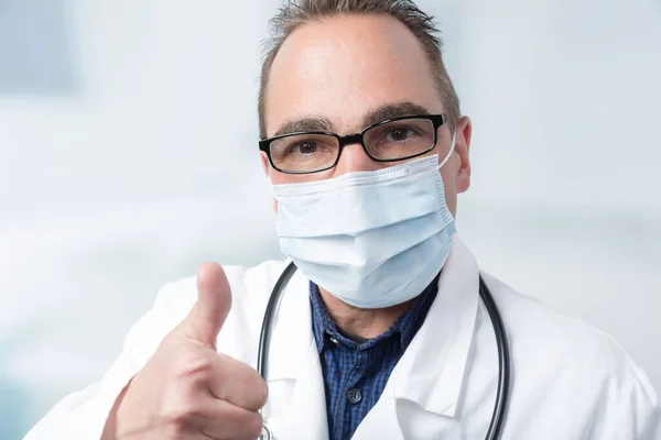 男医生在诊疗室前戴口罩和隐形眼镜 大拇指翘起 — 图库照片