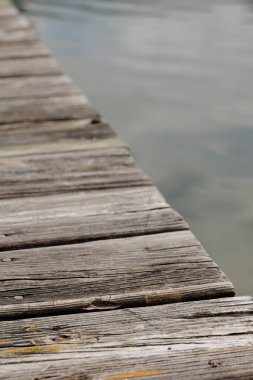 Göl suyunun üzerinde eski ahşap bir iskeleye yakın plan.