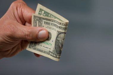 close-up of a man's hand holding a one dollar bill / one buck