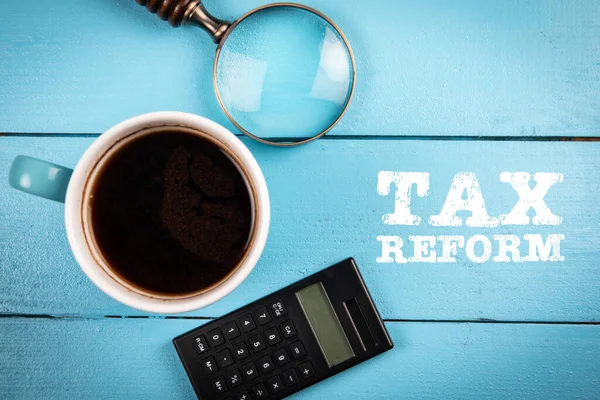 Reforma fiscal. Taza de café, lupa y calculadora sobre fondo de madera — Foto de Stock