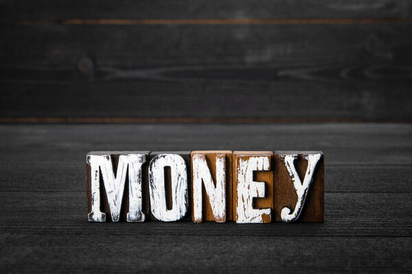 Money. Business, profits, taxes and bills concept. White wooden letters on a dark wooden background.