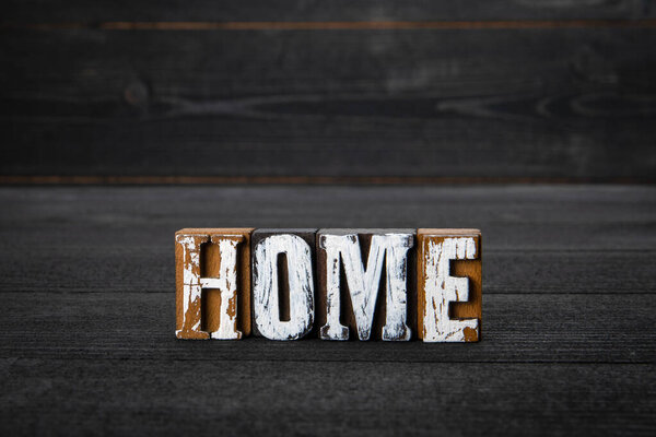 HOME. White wooden letters on a dark wooden background.