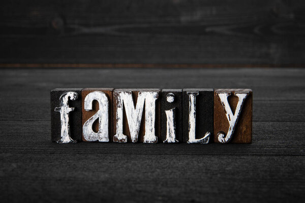 Family. White wooden letters on a dark wooden background.