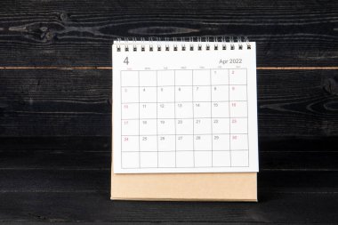 Nisan 2022. Siyah ahşap doku arka planında takvim ve planlayıcı