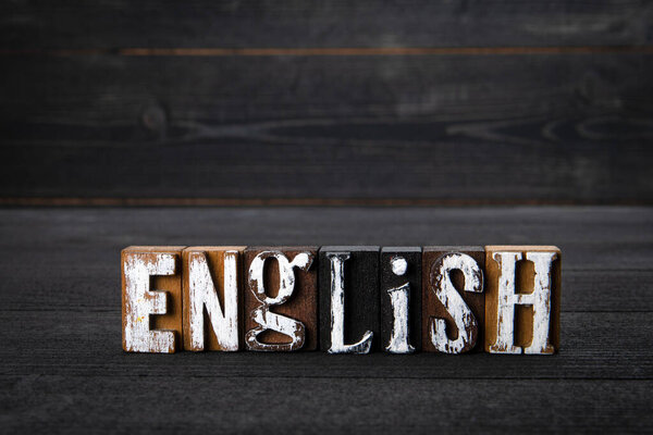 English. White wooden letters on a dark wooden background.