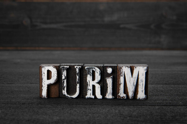 Purim. Holidays and traditions concept. Letters of the alphabet on a dark wooden background.