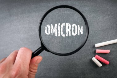 Coronavirus Covid-19 Omicron mutasyon varyantı. Bir erkeğin elinde büyüteç