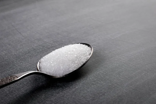 Teaspoon with white sugar on a chalk board background —  Fotos de Stock