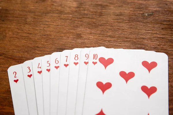 Playing cards with heart symbols on a wooden table — Stockfoto