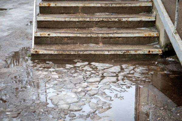 Dangerous and unsafe stairs. Melted snow, water and slippery. Concrete and rusty metal — Stock Photo, Image