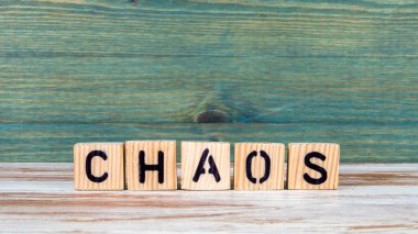 Kaos. Beyaz ve yeşil arkaplandaki tahta alfabe bloklarından metin