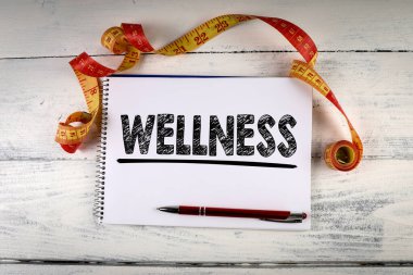 Sağlıklılık. Tahta bir masada mezura, kalem ve defter ölçüyorum.