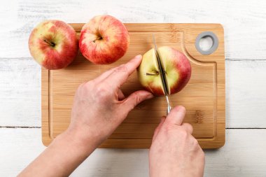 Kadın eli bıçakla bambu kesme tahtasındaki elmayı kesti. Sağlıklı ve doğal ürün
