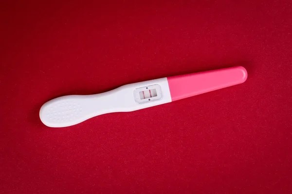 Teste de gravidez positivo em um fundo vermelho — Fotografia de Stock