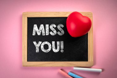 Özledim seni. Tebeşir tahtası, pembe arka planda kırmızı kauçuk kalp.