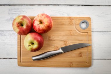 Taze elmalar ve bambu kesme tahtasındaki paslanmaz çelik bıçak.