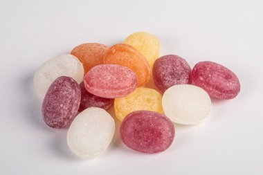 Beyaz arka planda renkli şekerler yığılmış. Lolipoplar ve şekerler