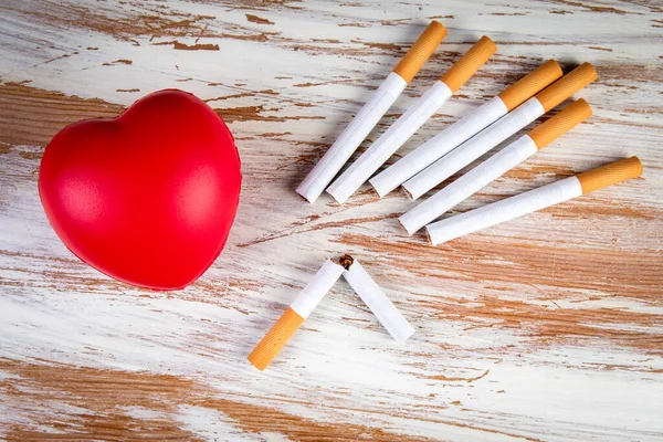 Кинути палити. Гумове серце і сигарети на дерев'яному тлі. Серцево судинне здоров'я — стокове фото