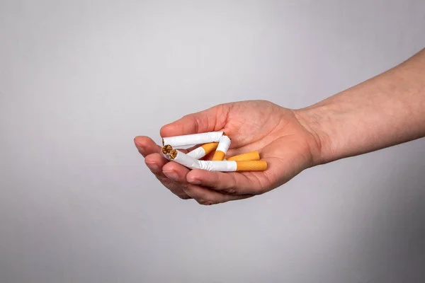 Σπασμένος σωρός από τσιγάρα σε γυναικείο χέρι. Κόψε το κάπνισμα. — Φωτογραφία Αρχείου