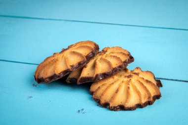 Mavi desenli ahşap arka planda çikolatalı kurabiyeler.