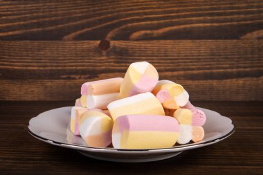 Beyaz bir tabağa konmuş renkli marşmelov parçaları.