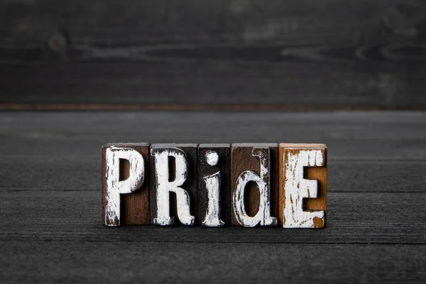 Pride. Text from alphabet letters on a black wooden background — 스톡 사진