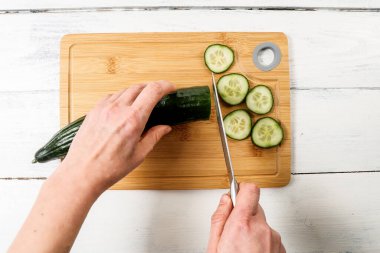 Bıçaklı kadın elleri taze salatalık kesiyor. Yiyecek ve vitaminler.