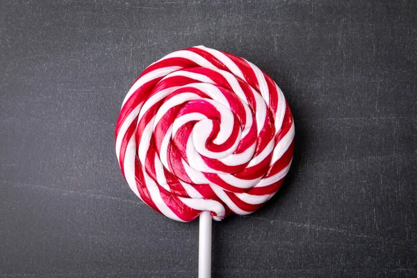 Red, round candy on a dark chalkboard background — Stock Photo, Image