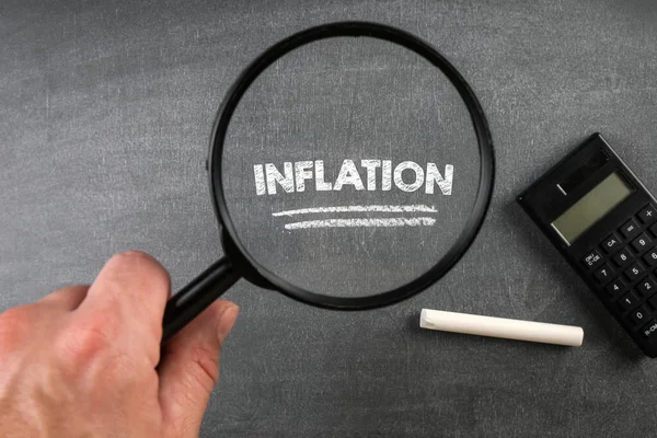 Inflation. Calculator and magnifying glass on a chalkboard background — Stock Photo, Image