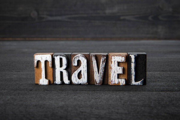 TRAVEL. Word from wooden alphabet blocks on a dark background