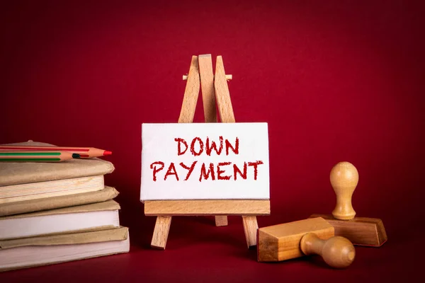 DOWN PAYMENT. Miniature easel, books and stamps on a red background — Stockfoto