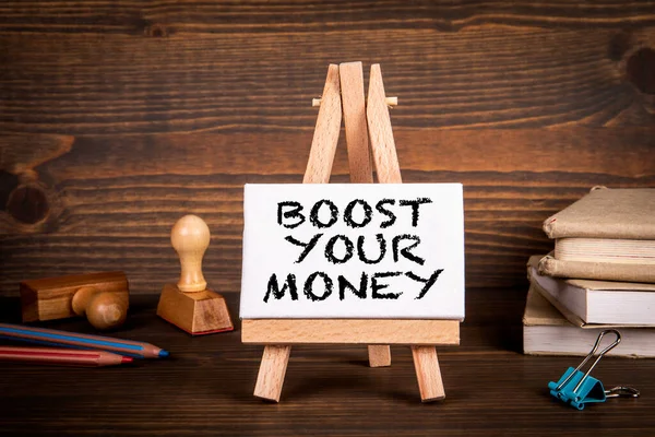 BOOST YOUR MONEY. Miniature easel on a wooden office desk — Foto de Stock