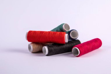 Beyaz arkaplanda farklı renklerde iplik makaraları