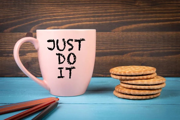 JUST DO IT. Coffee mug with text. blue and brown wooden background.