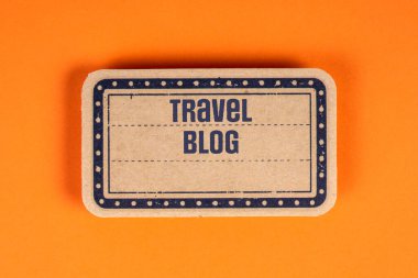 Travel Blog. Text on a decorative label sheet.Orange background.