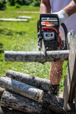 Elektrikli testere ile uzun bir kütüğü parçalara ayırmak. Kışın ısıtma mevsimi için yakacak odun sağlıyorum..
