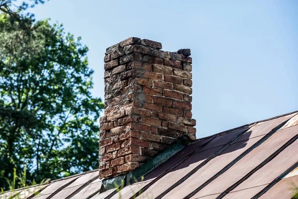 Old brick chimney in need of repair on a roof. Heating and fire safety concept.