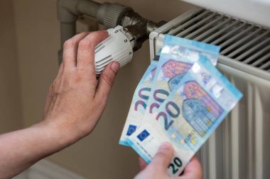 Radiator with adjustable intensity to reduce costs. Euro money, energy crisis.