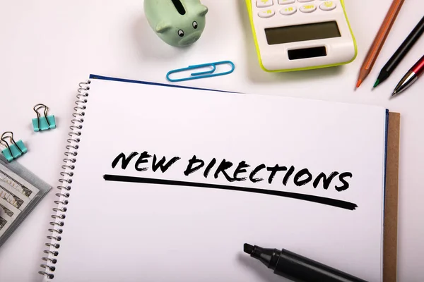 NEW DIRECTIONS. Text on paper. Office supplies on the table.