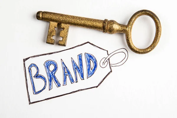 Brand, business concept. Gilded door key on a white background.