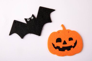 Gülümseyen bir balkabağı ve beyaz arka planda bir yarasa. Cadılar Bayramı süslemeleri.