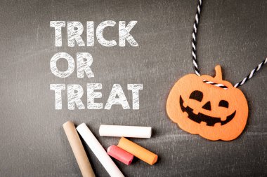 Şeker mi şaka mı? Kara tahta arka planında metin ve dekoratif balkabağı.