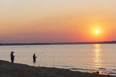 Dallas, Teksas yakınlarındaki Lavon Gölü 'nde gün doğumunda bot ve şapka balıkçılığı yapan iki Asyalı adam.