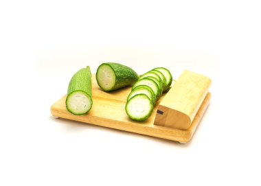 Beyaz arka planda izole edilmiş ahşap bir kesme tahtasının üzerinde yarım dilim Asya lifinden bir sürü var. Organik tropikal luffa hazırlığı hazır..